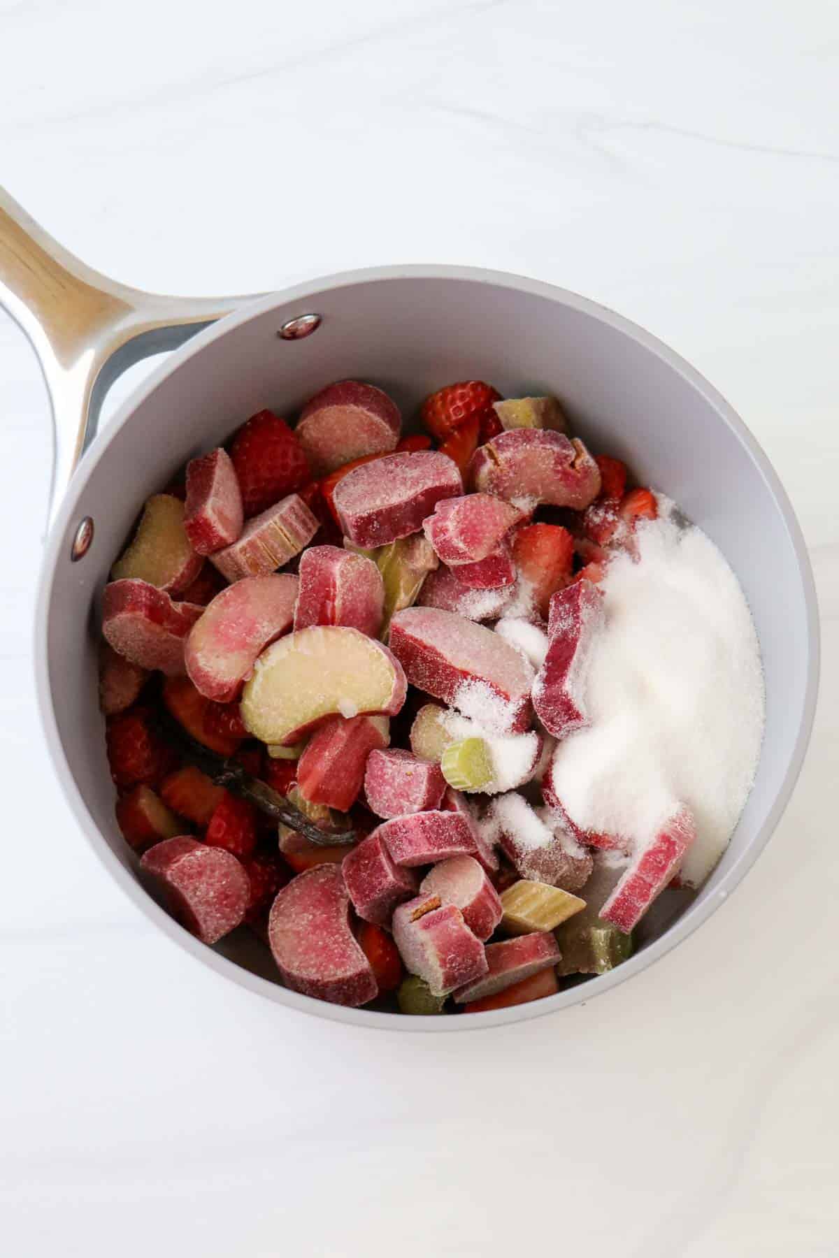 Rhubarb and strawberries in a saucepan with sugar.