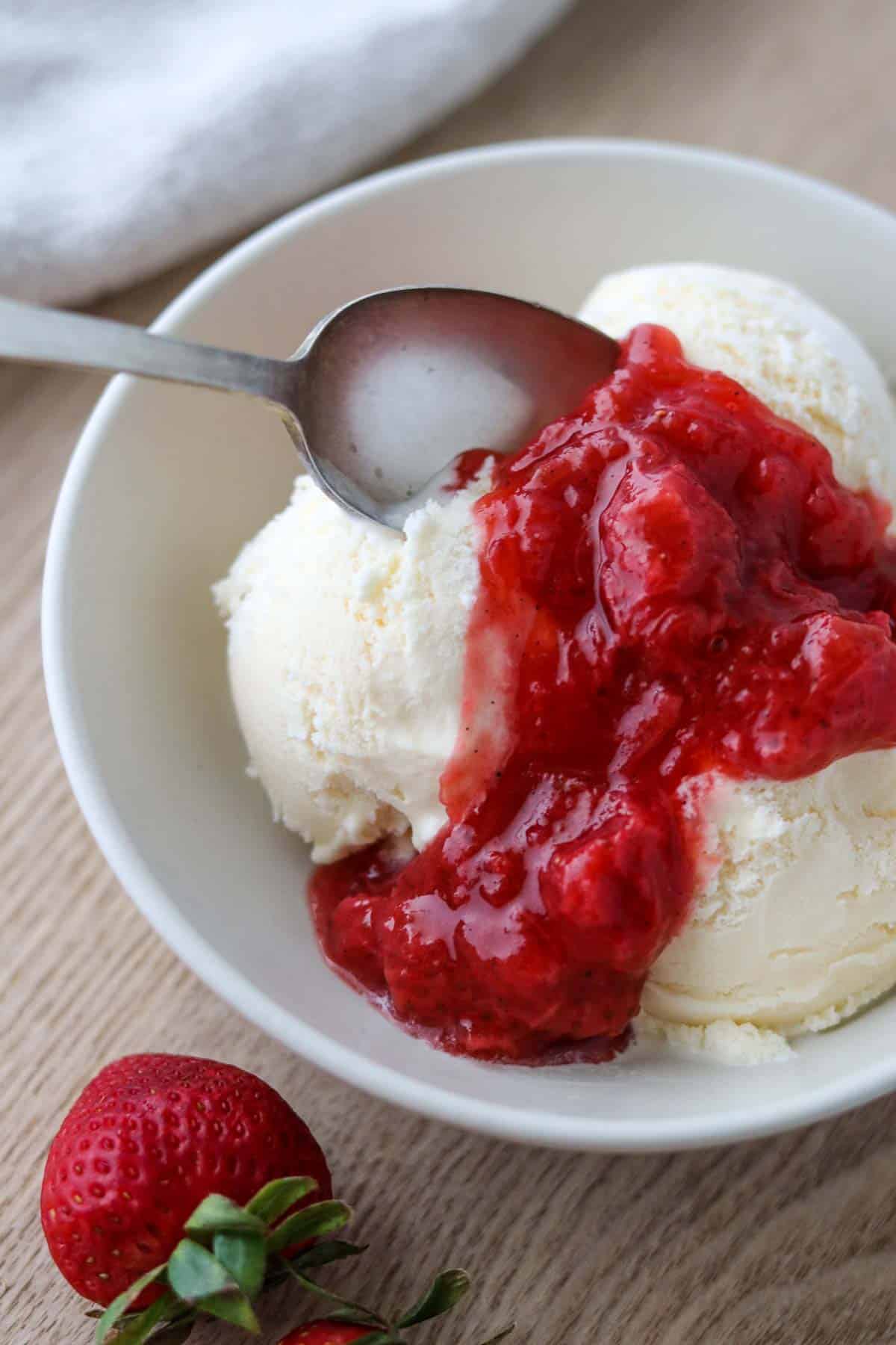 Vanilla ice cream in a bowl topped with Strawberry Rhubarb Compote