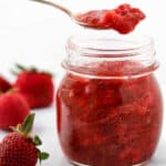 Close up of Strawberry Rhubarb Compote in a jar with a spoon.
