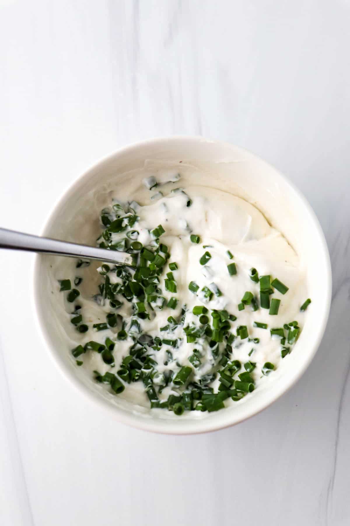 Horseradish Yogurt Sauce in a white bowl topped with chopped fresh chives.
