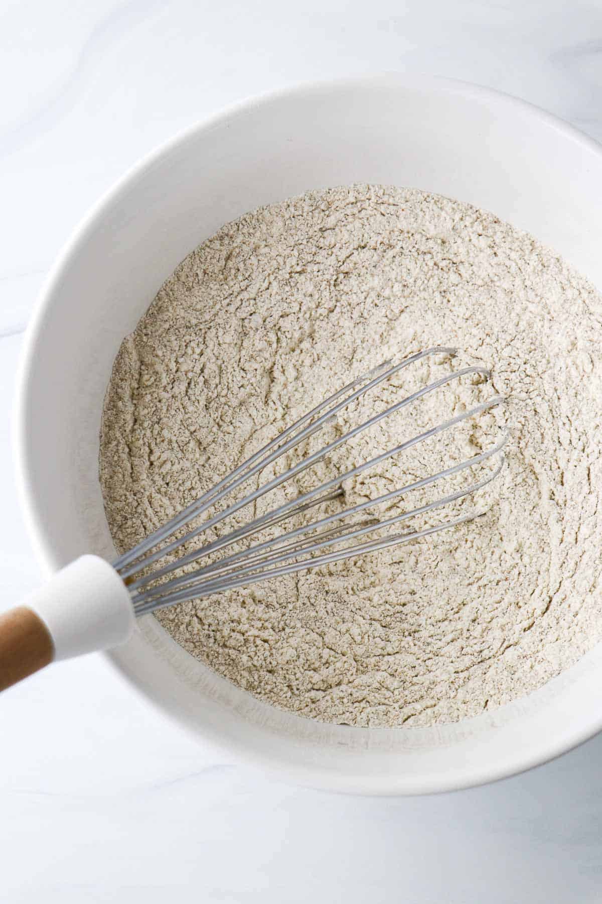 Flour in a white bowl with a whisk.