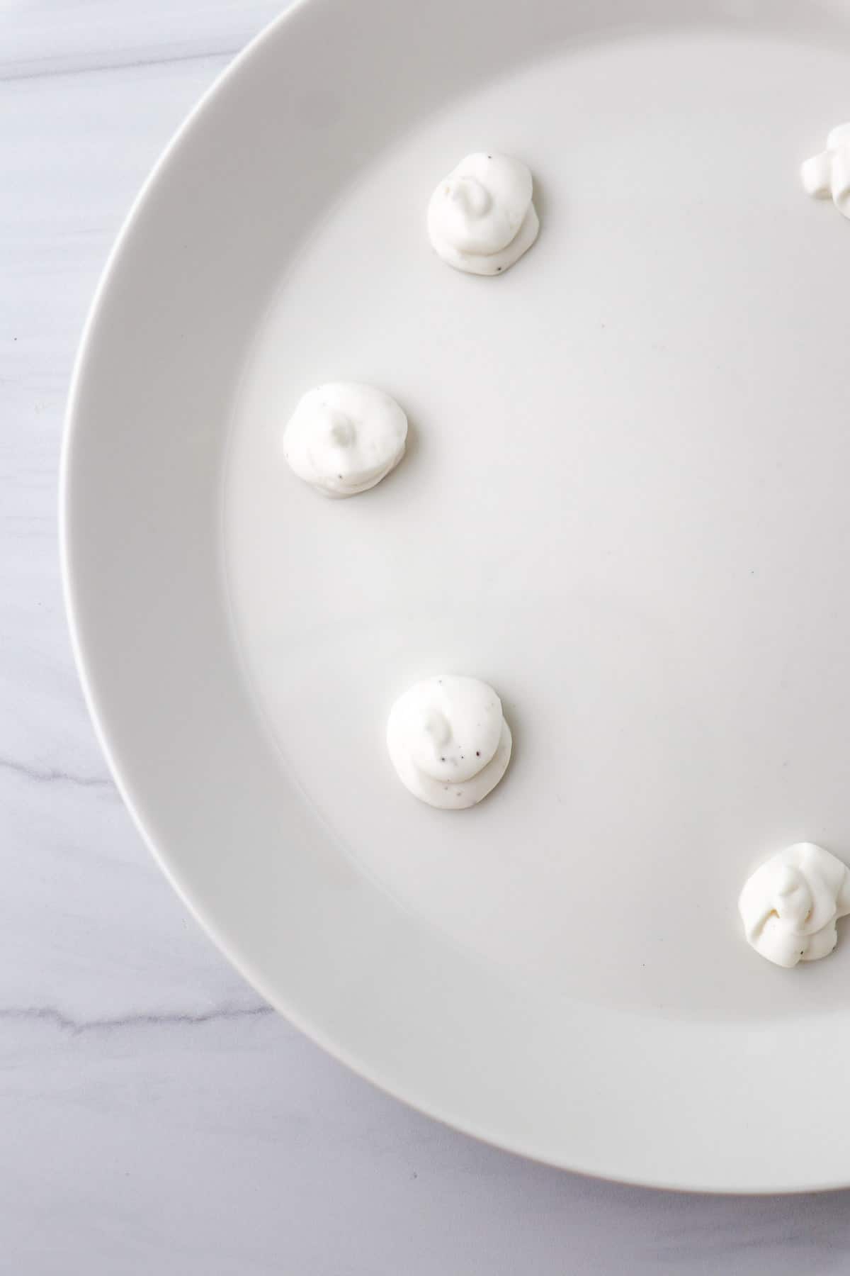 Dollops of Horseradish Yogurt Sauce in a circle on a white plate.