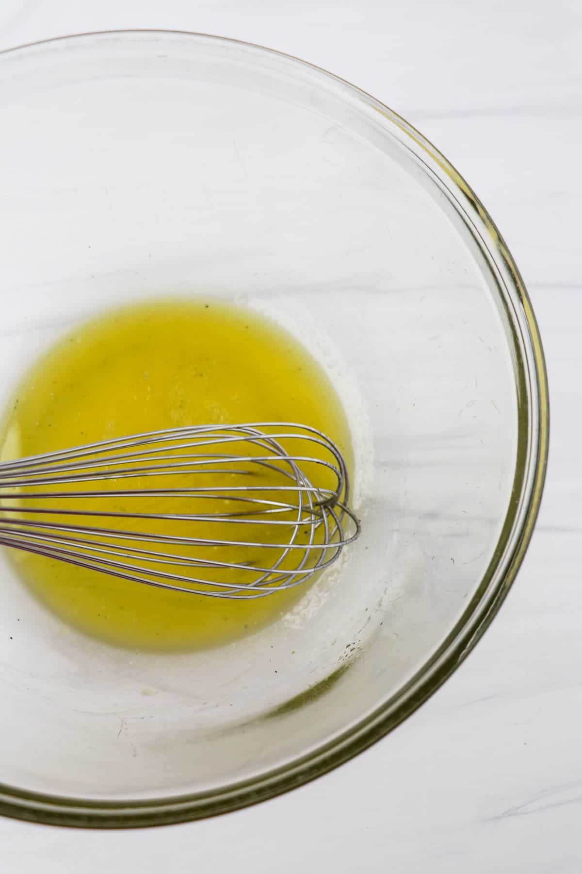 Vinaigrette in a glass bowl with a whisk.