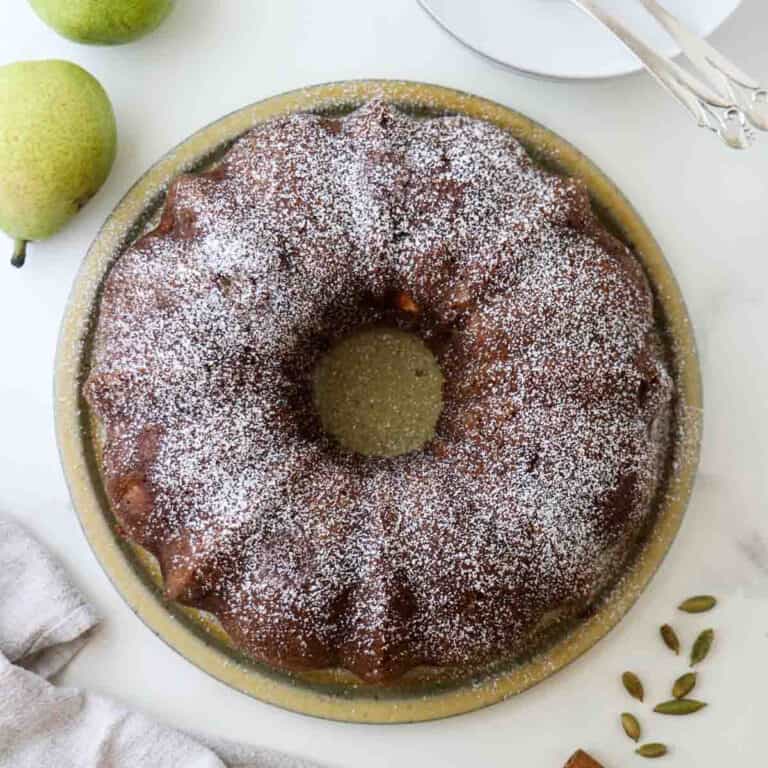 Overhead view of Spiced Pear Cake with Cardamom next to pears and cardamom pods.