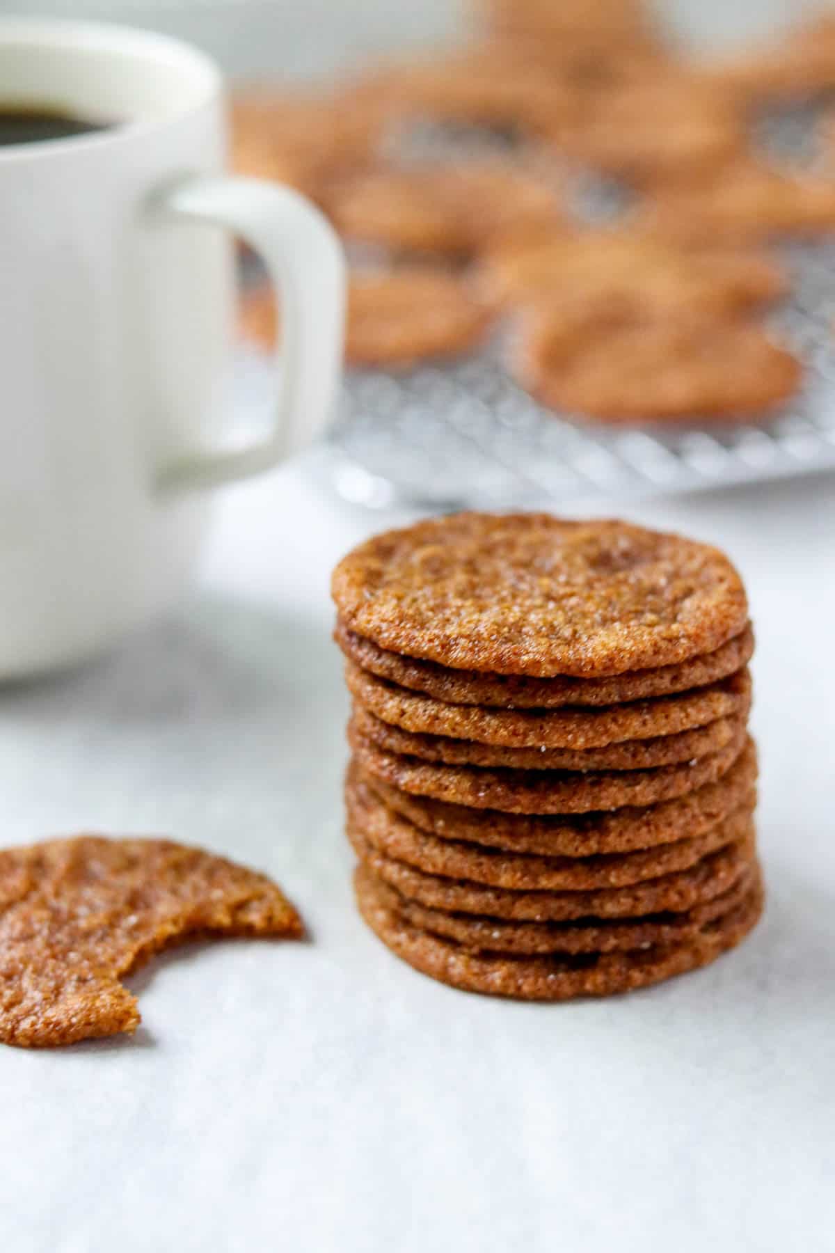 A stack of Swedish Ginger Cookies next to a cup of coffee.
