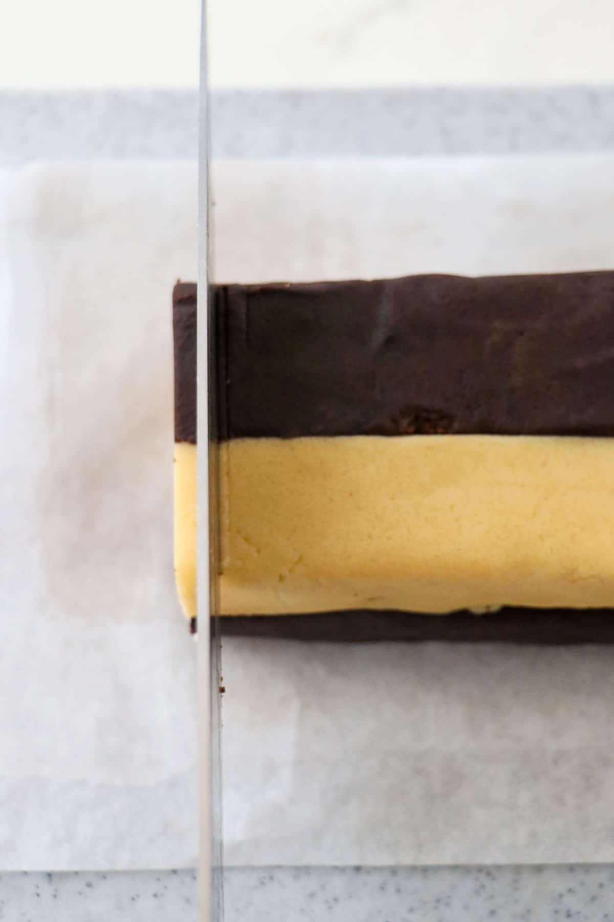 Knife cutting into checkerboard cookie dough.