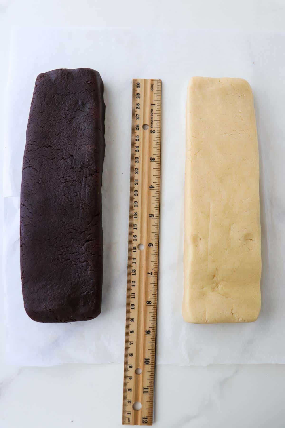 Two rectangles of cookie dough, one chocolate and one vanilla with a ruler in between them.