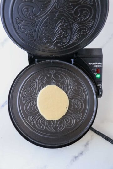 Krumkake batter on a krumkake iron.