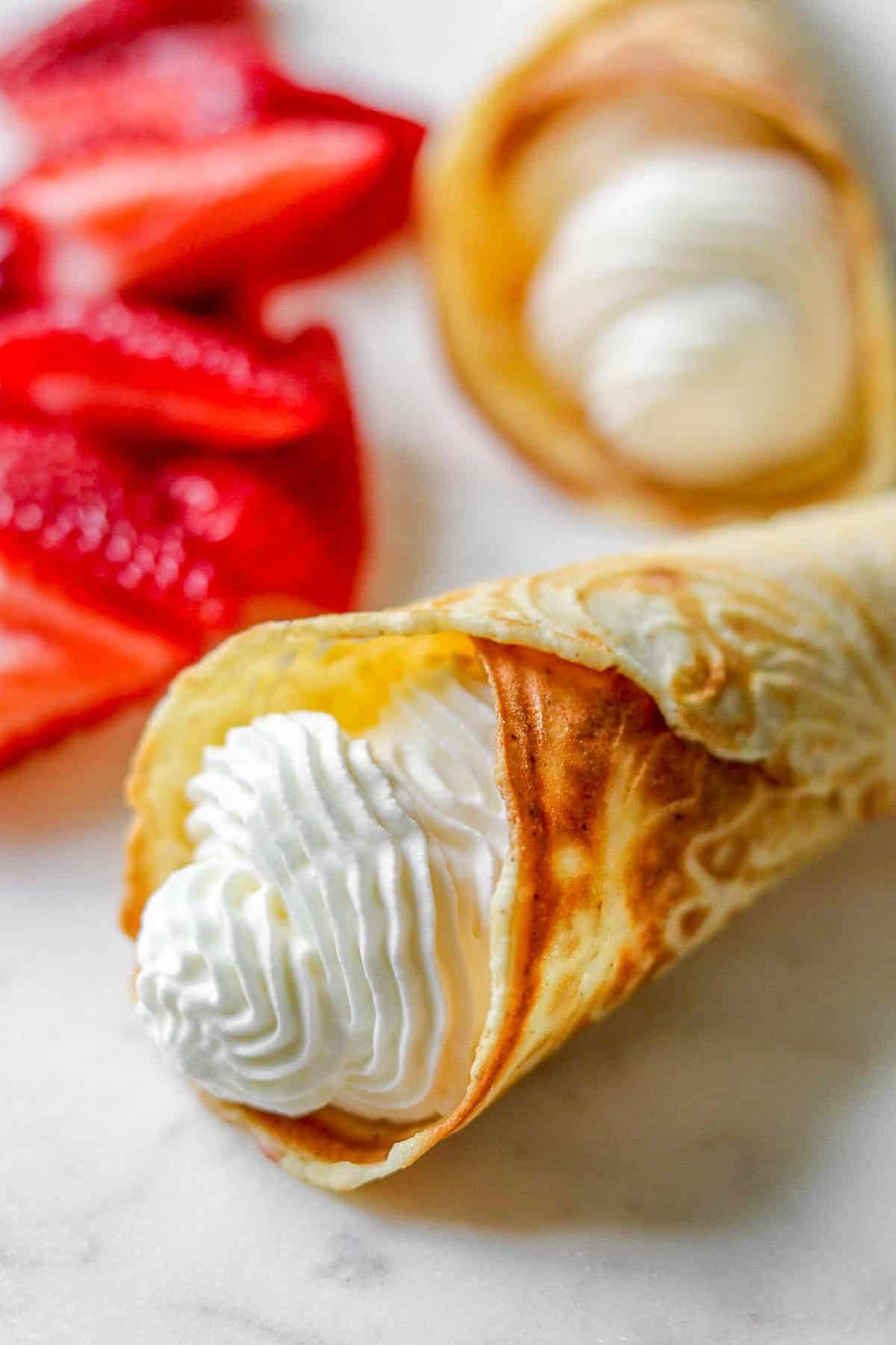 Close up of a krumkake filled with whipped cream.