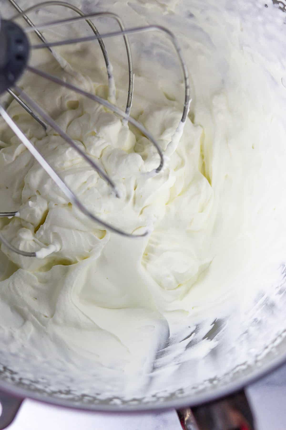 Whipped cream in a mixer bowl with a whisk attachment.