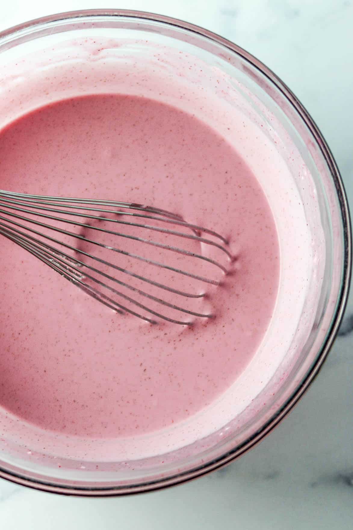 Lingonberry Mousse (Trollkrem) in a glass bowl with a whisk.