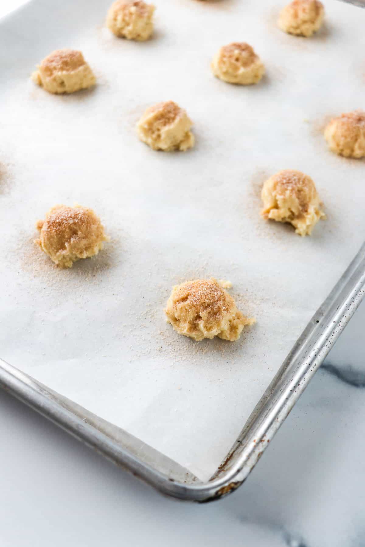 Unbaked Old-Fashioned Buttermilk Cookies on a baking sheet sprinkled with cinnamon and sugar.