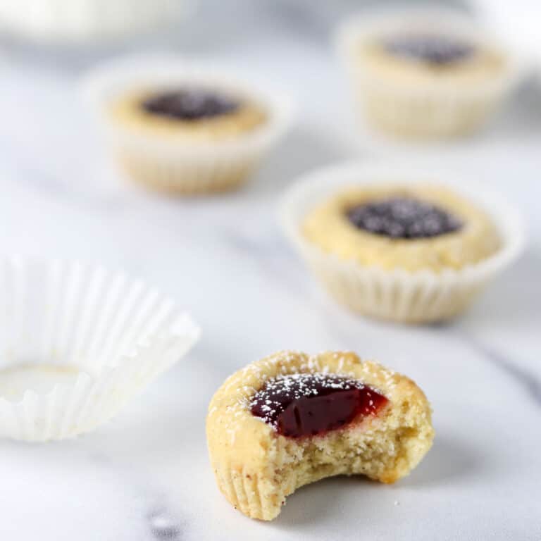 Close up of a raspberry hazelnut thumbprint cookie with a bite out of it.