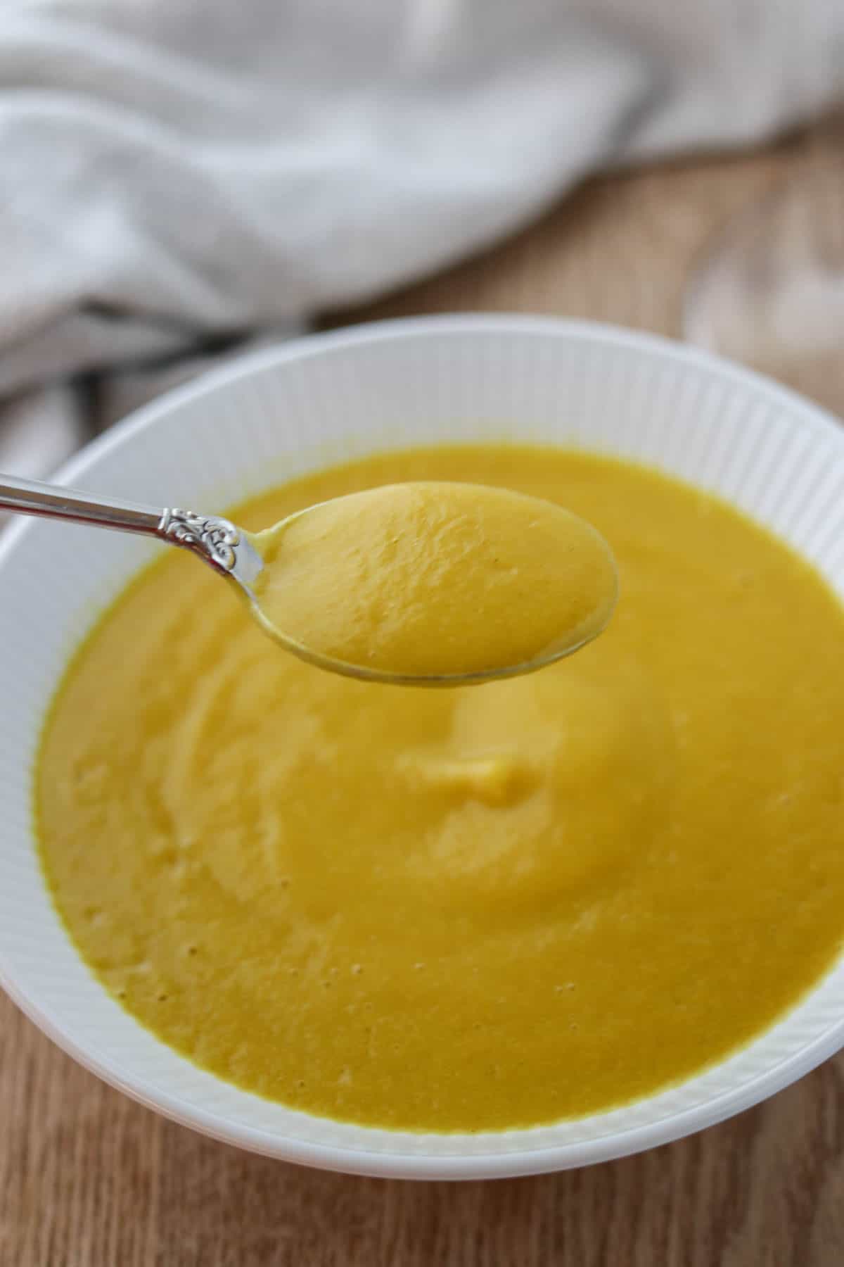 Spoonful of Golden Beet Soup held over a bowl of soup.