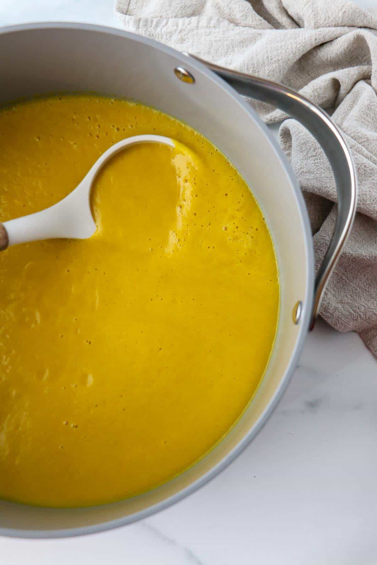 Pot of Golden Beet Soup with a white ladle.