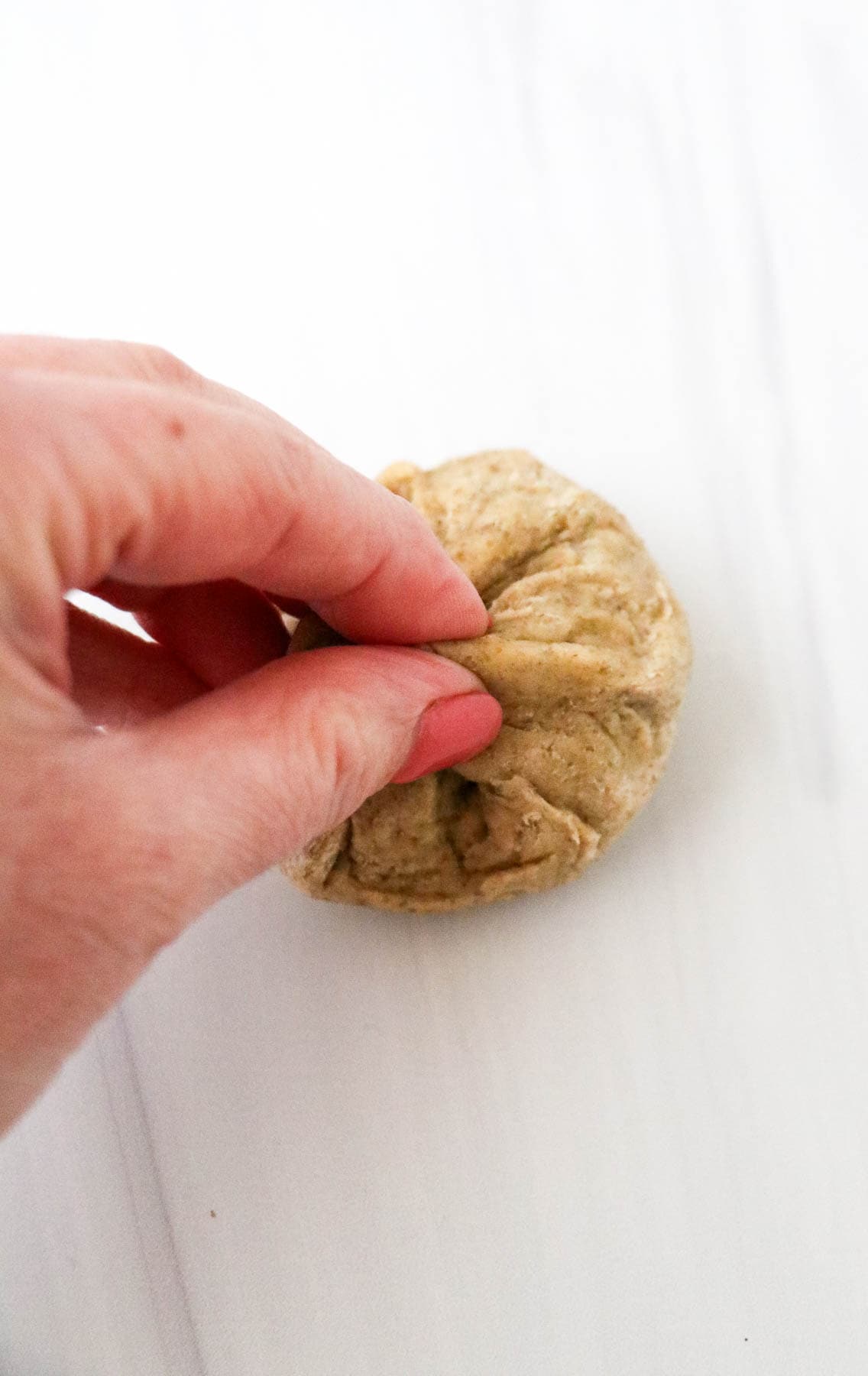 Person pinching piece of rye dinner roll dough.