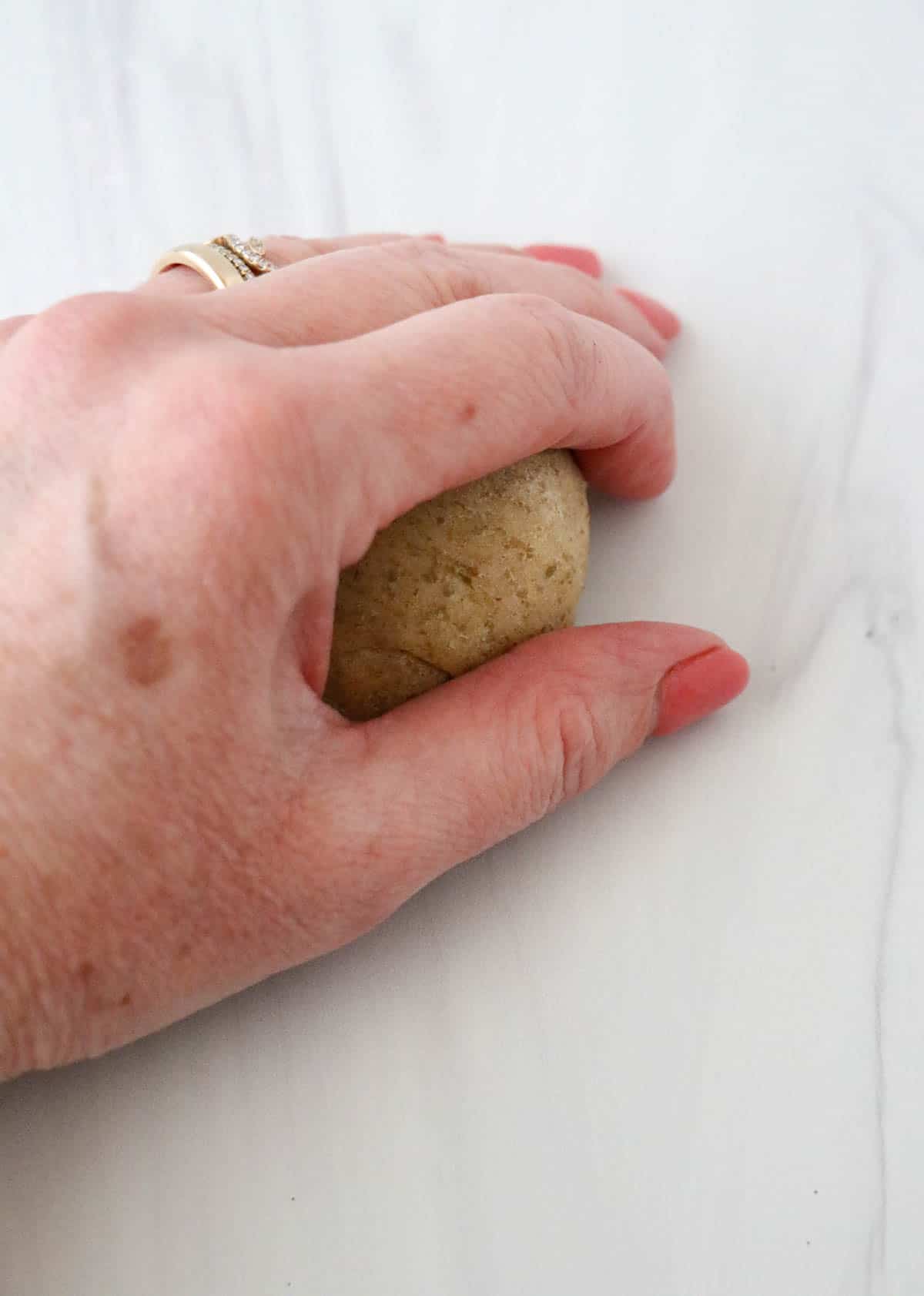 Person rolling rye bread dough into roll shape.