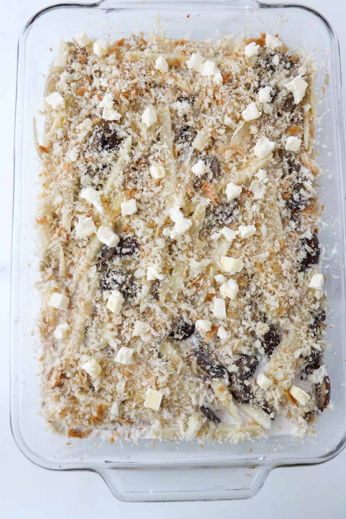 Unbaked Vegetarian Jansson's Temptation topped with bread crumbs and butter.
