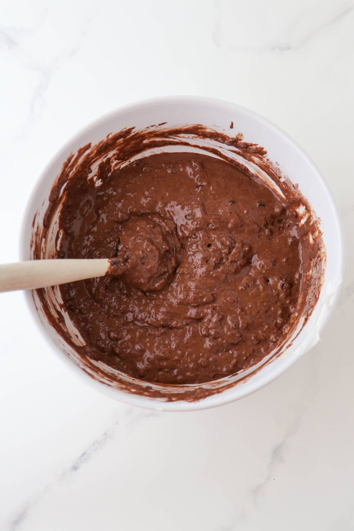 Chocolate waffle batter in a bowl with a rubber spatula.