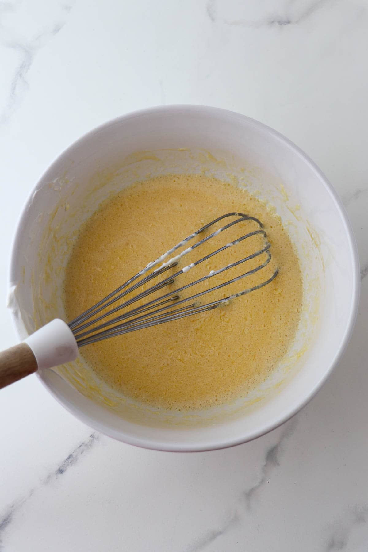 Wet ingredients for chocolate waffles in a bowl with a whisk.