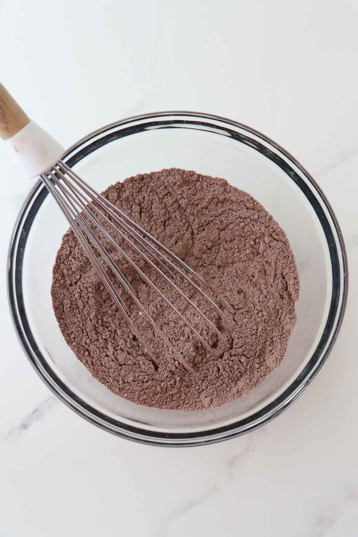 Dry ingredients for chocolate waffles in a bowl with a whisk.