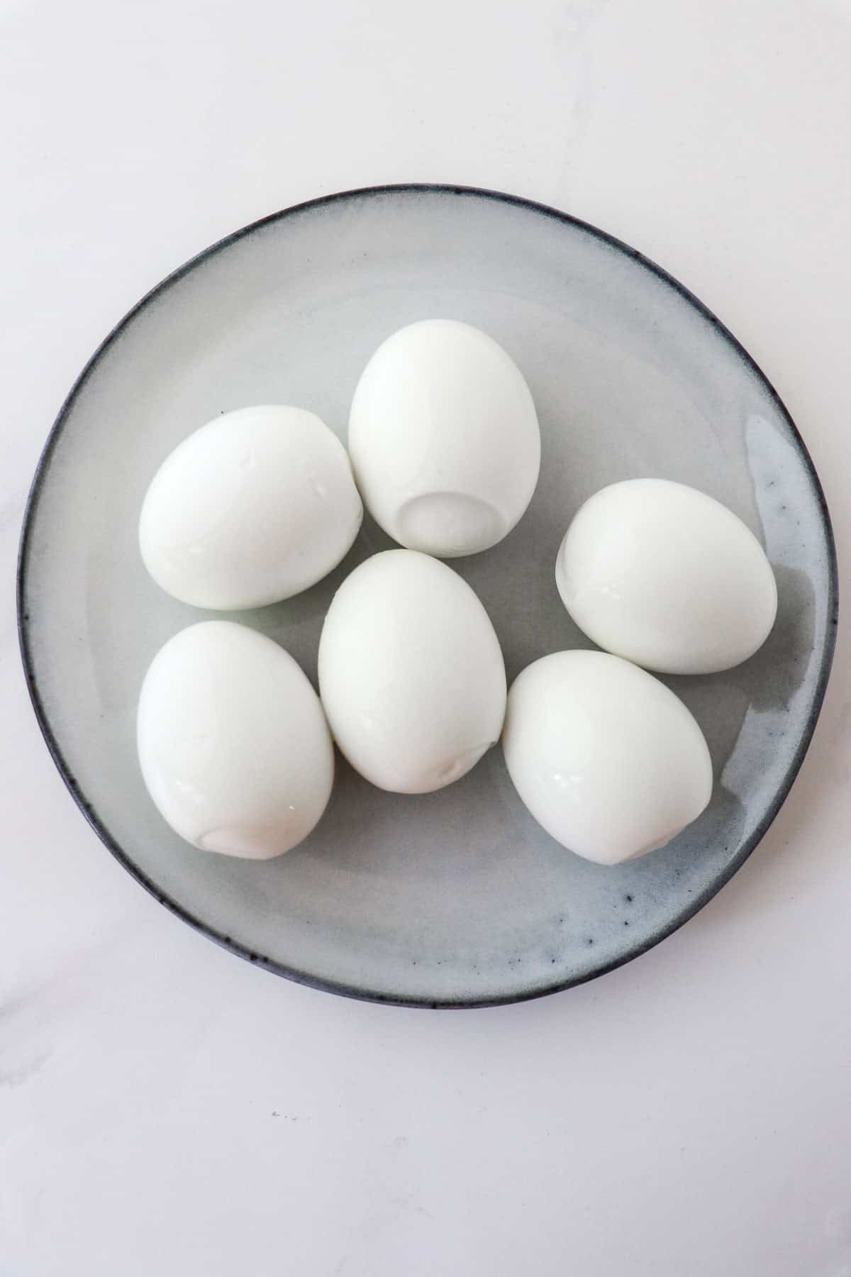 Peeled hard-boiled eggs on a plate.
