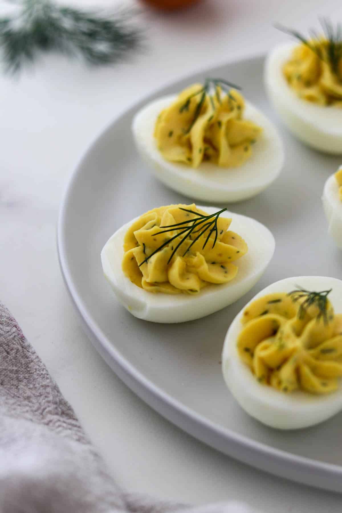 Deviled Egg with Dill on a plate topped with a sprig of dill.