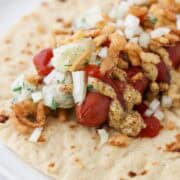 Hot dog on top of a tortilla topped with potato salad, onions, mustard and ketchup.