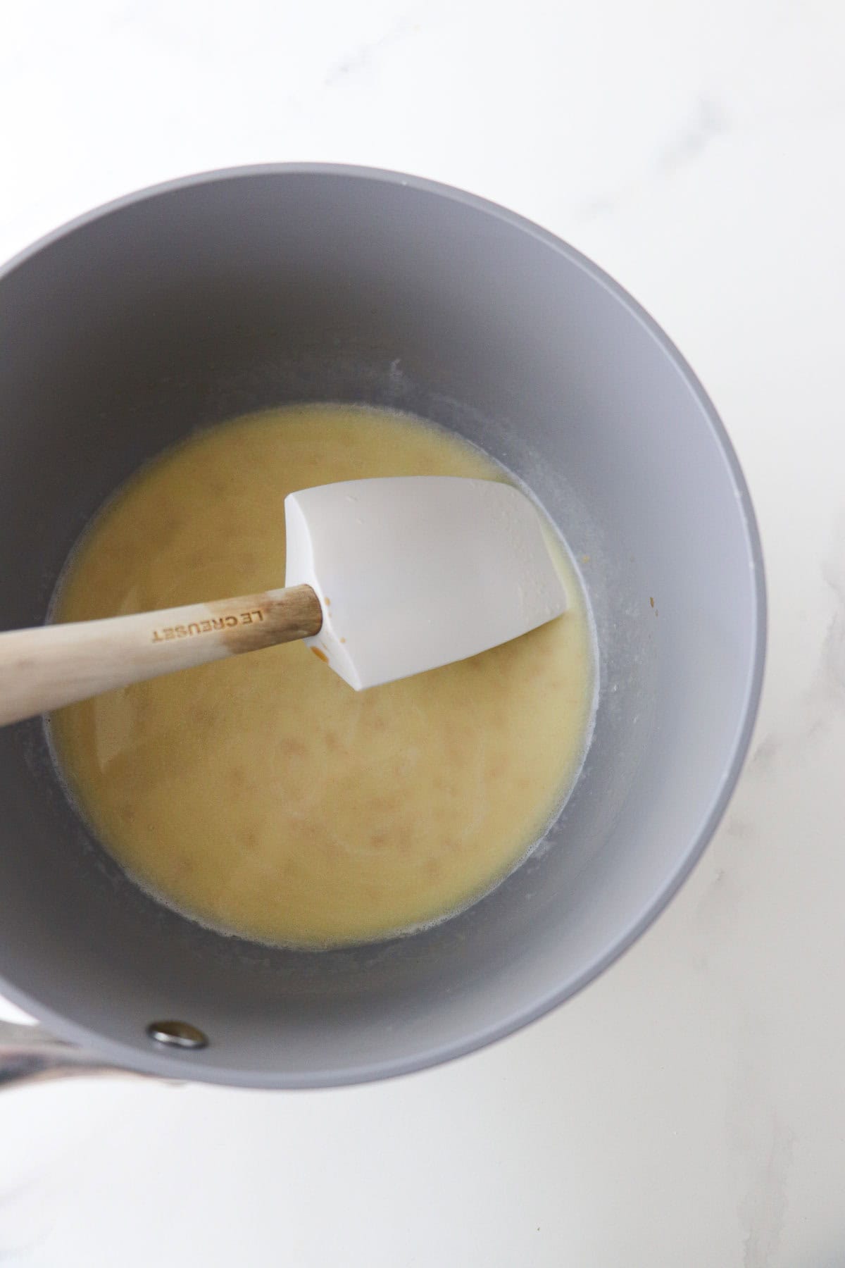 Butter and milk melted together in a saucepan with a rubber spatula.