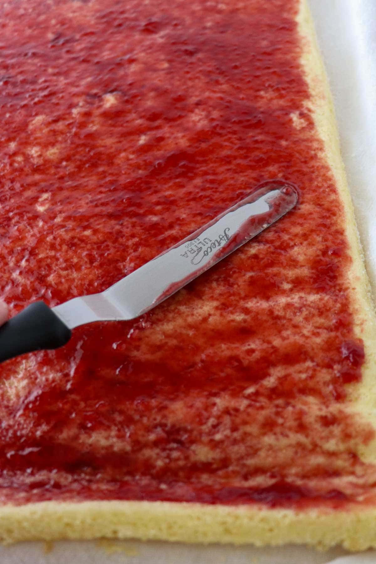 Swedish Rulltårta being spread with raspberry jam.