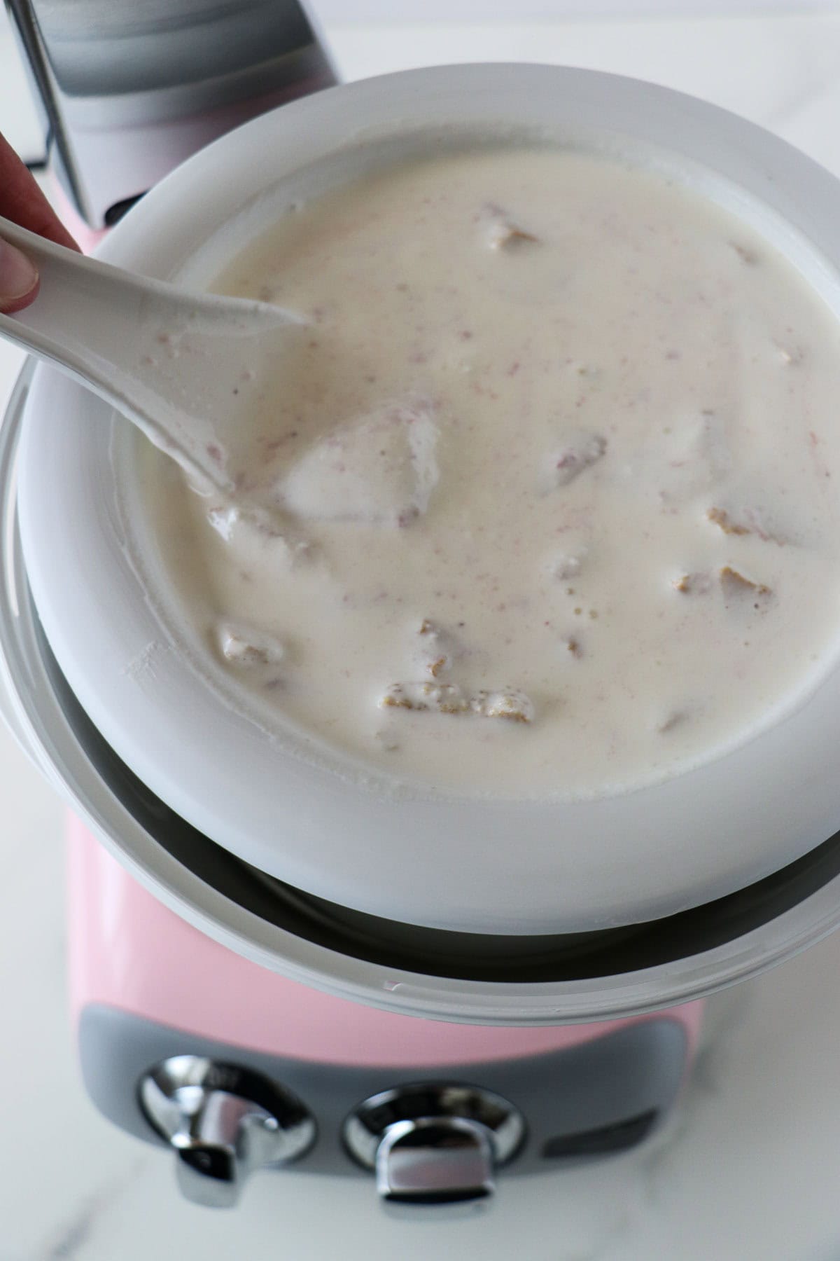 Person swirling graham crackers and jam into ice cream base.