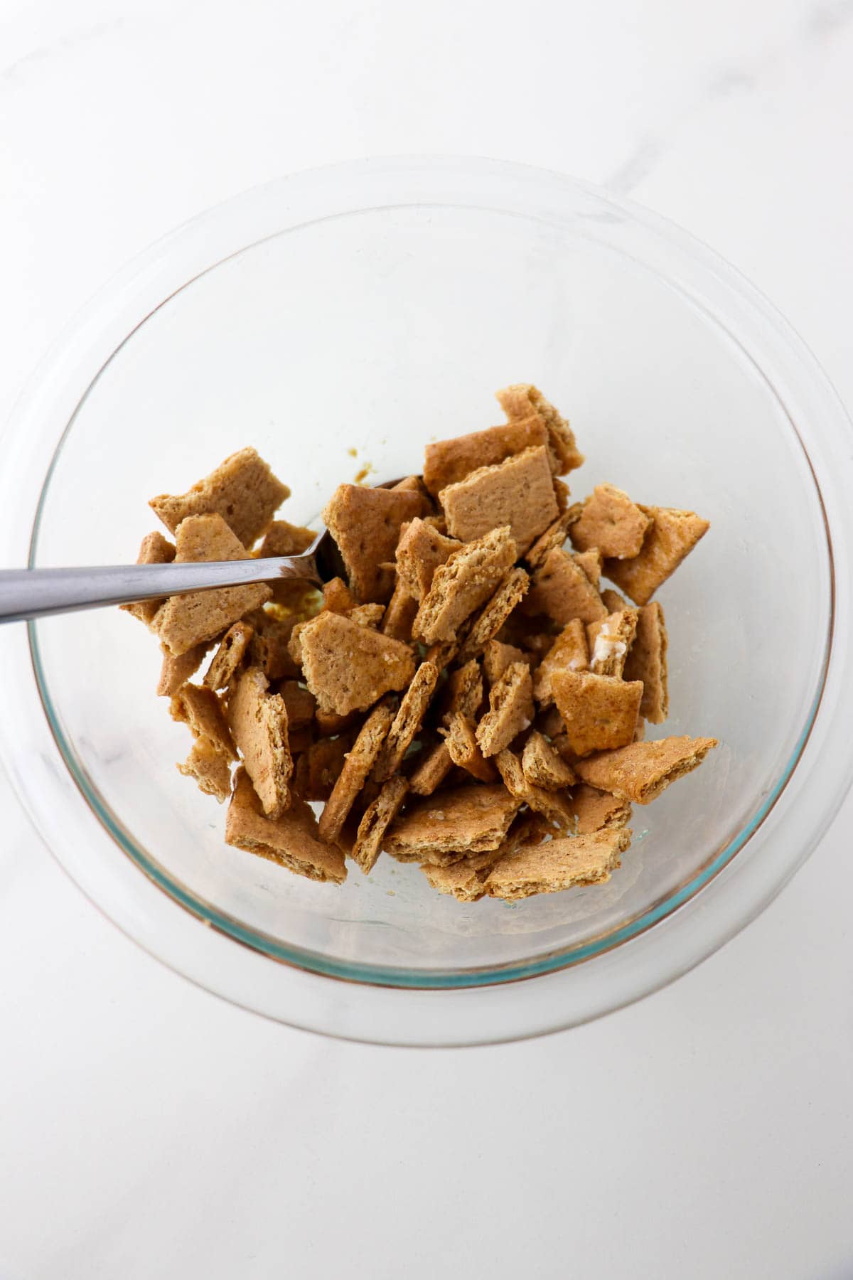 Crushed up graham crackers in a bowl with a spoon.