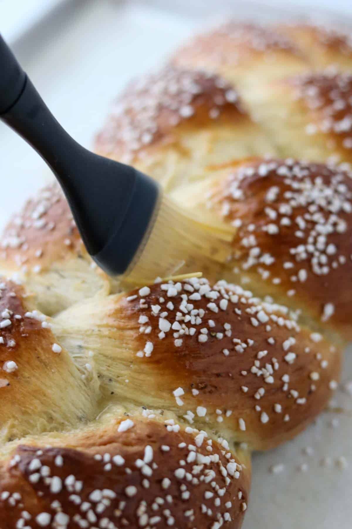 Person brushing butter on loaf of Cardamom Bread (Finnish Pulla).