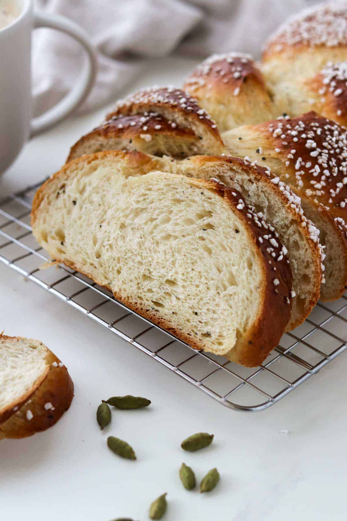 cardamom-bread-pulla-11 Cardamom Bread (Finnish Pulla) on a cooling rack next to coffee and cardamom pods.