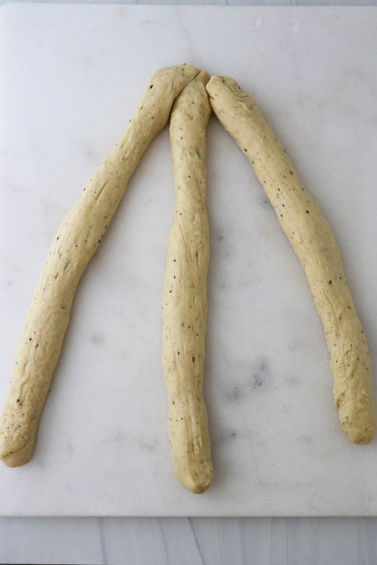 Three ropes of bread dough ready to be braided together.