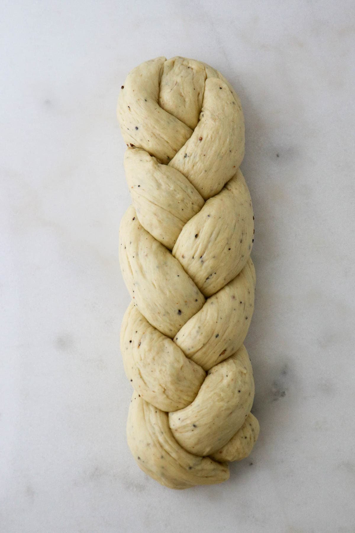 Braided loaf of Cardamom Bread (Finnish Pulla) on a marble surface.