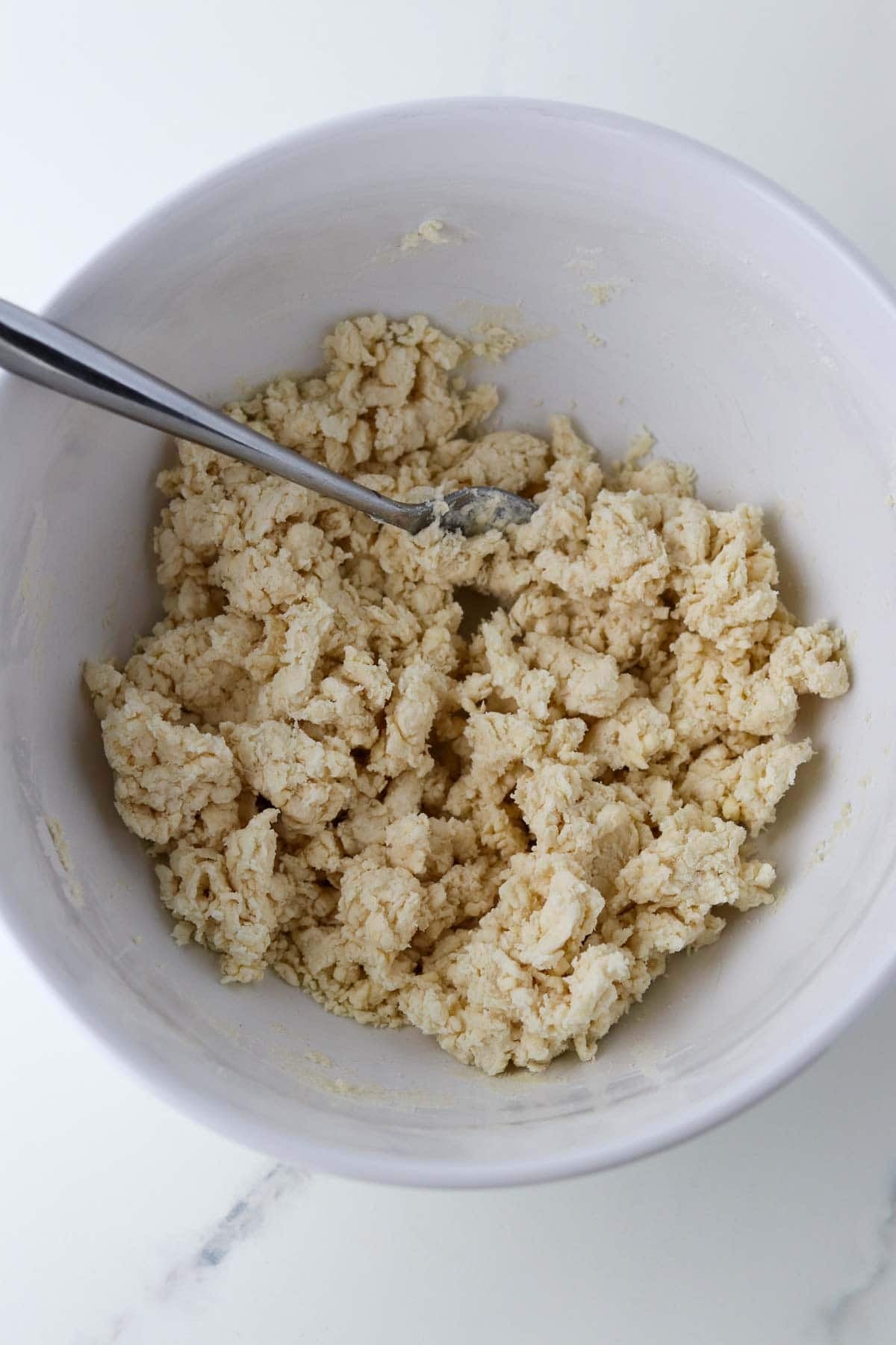 Cardamom Peach Cobbler dough in a white bowl with a fork.