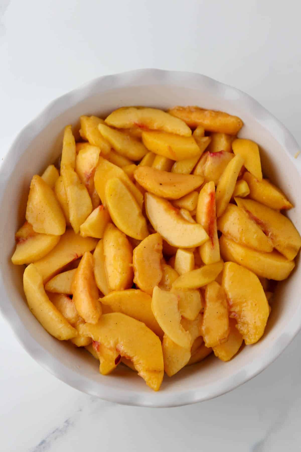 Peaches in a white pie plate.