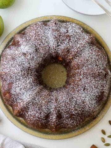Cozy spiced pear cake next to pears and cardamom pods.
