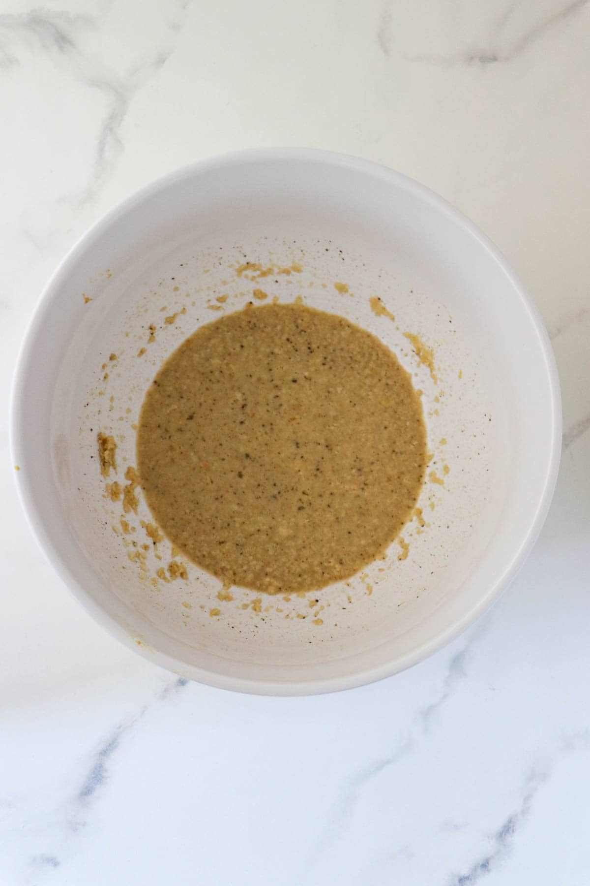 Wet ingredients for Danish Meatloaf whisked together in a white bowl.