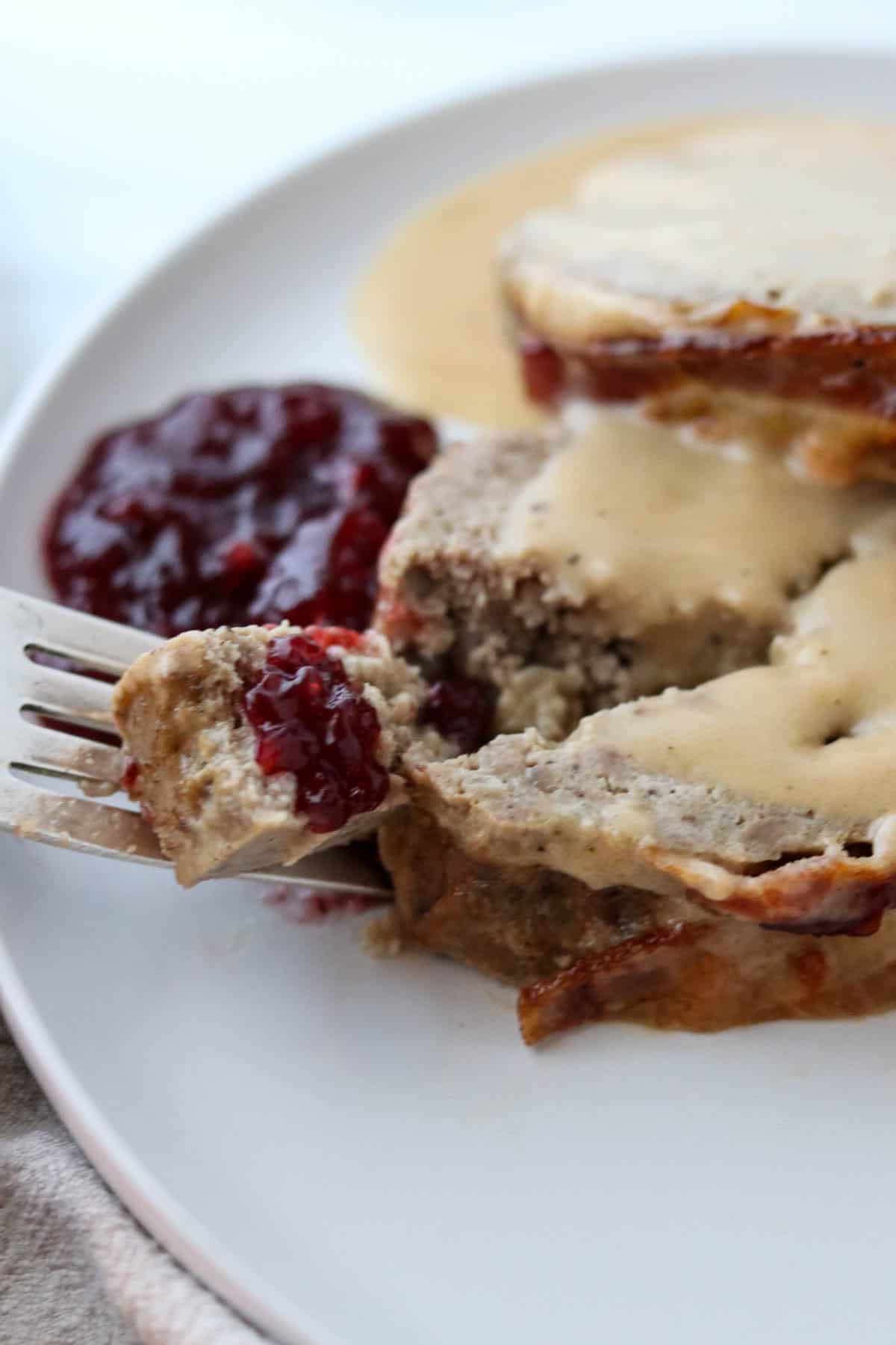 A bite of Danish Meatloaf on a fork with lingonberries.