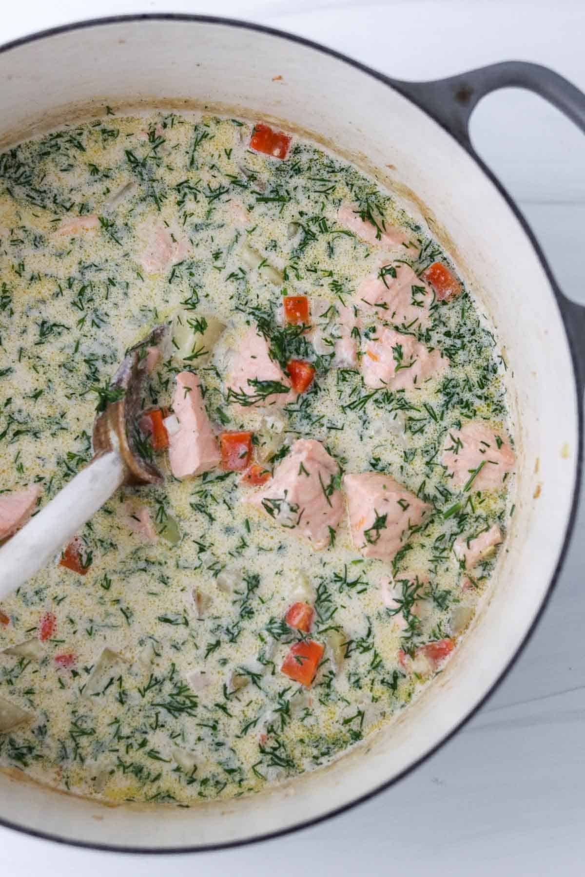 Traditional Finnish Salmon Soup (Lohikeitto) in a pot with a wooden spoon.