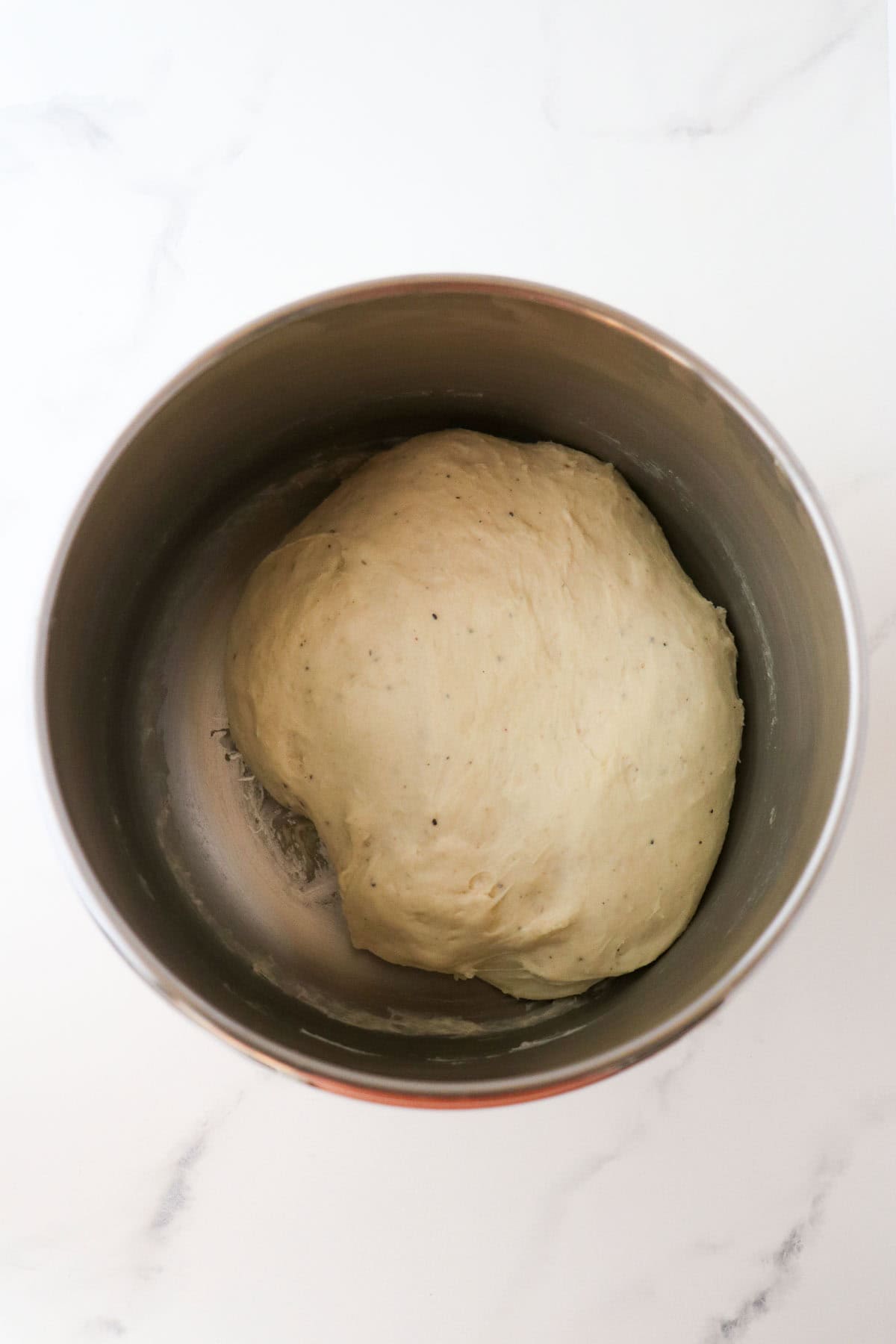 Fully proofed cinnamon bun dough in a metal bowl.