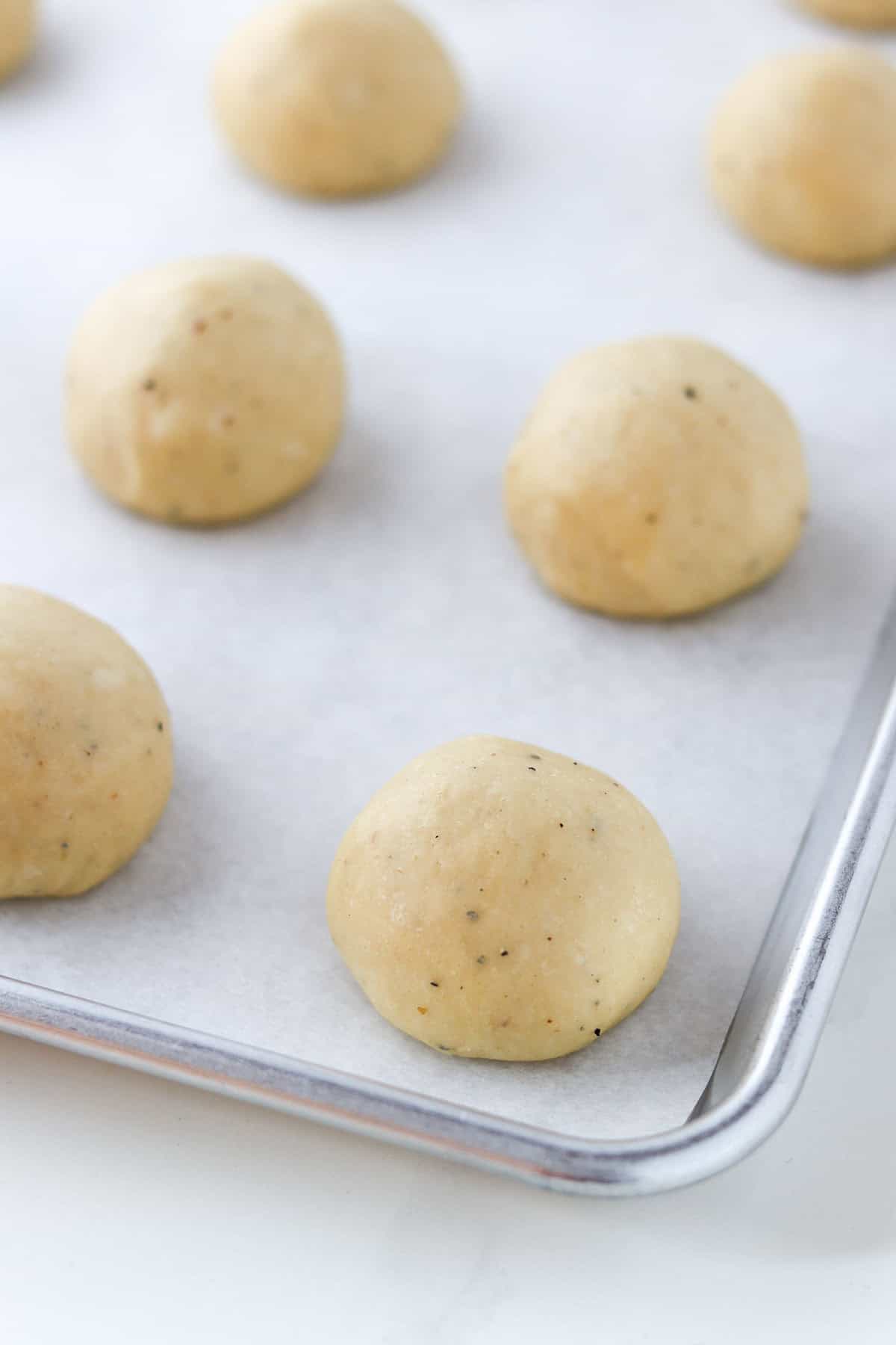 Shaped and unbaked Fastelavnsboller (Norwegian Lenten Buns) on a baking sheet.