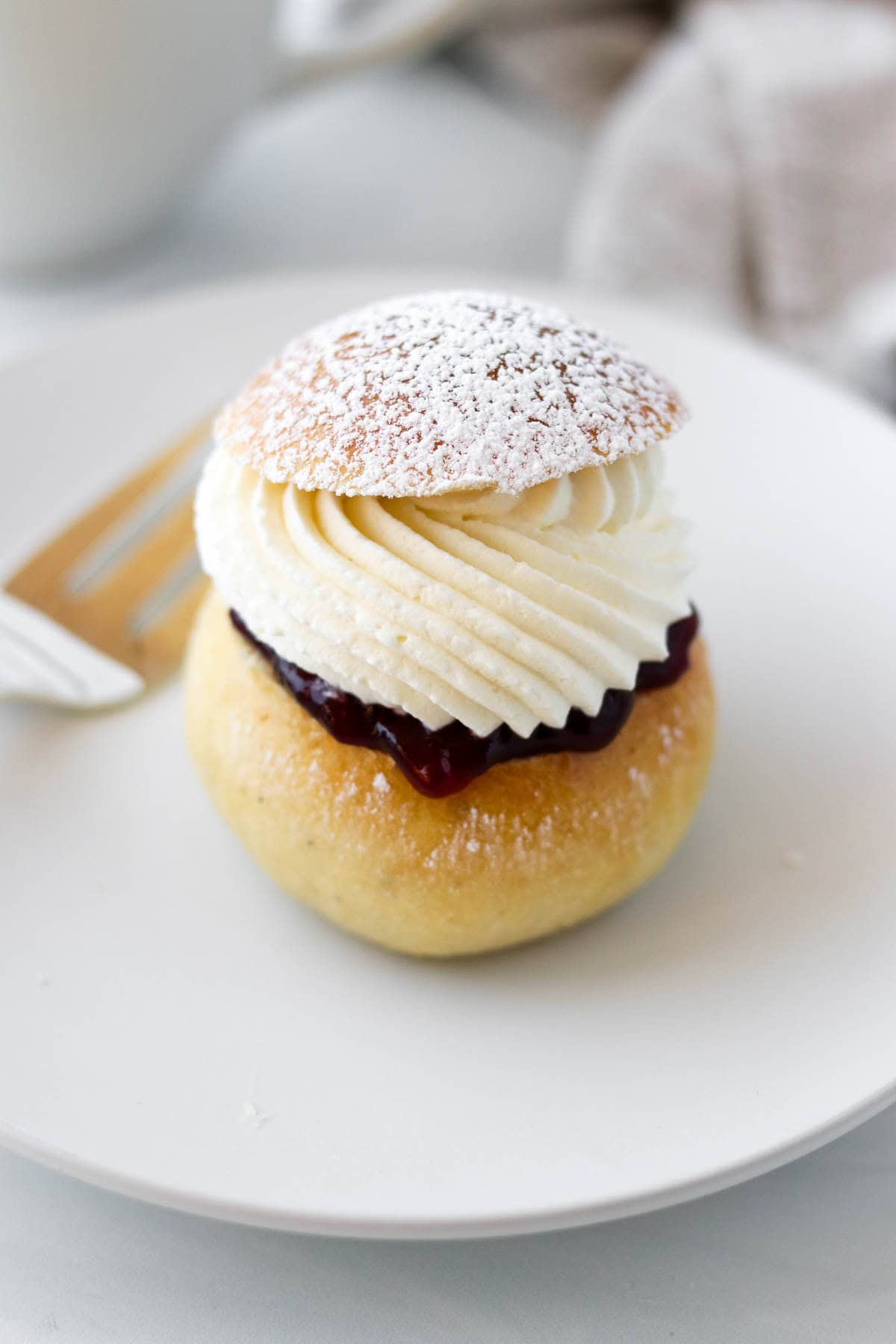Fastenlavnsboller(Norwegian Lenten Bun) sprinkled with powdered sugar on a white plate.