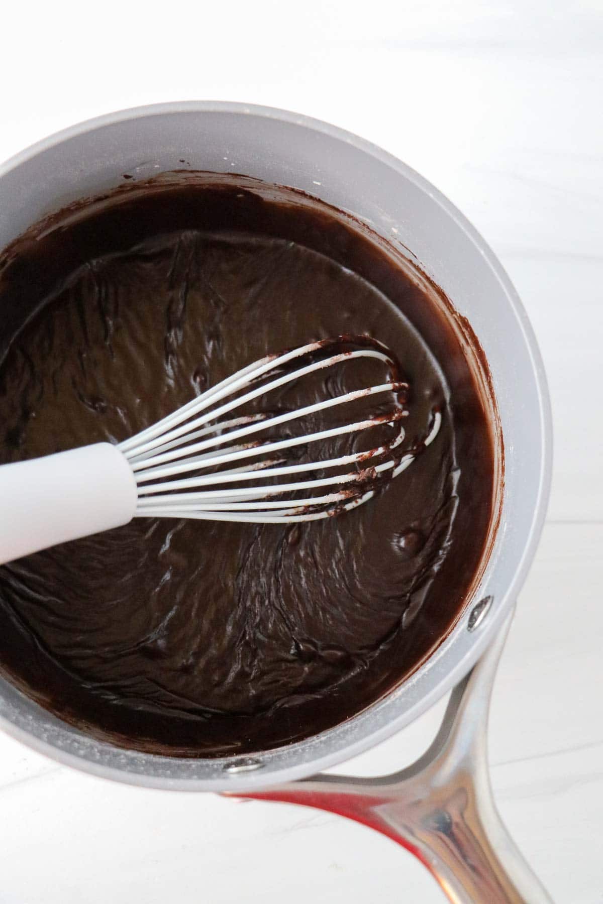 Mocha glaze for Swedish Love Cake (Kärleksmums) in a saucepan with a whisk.