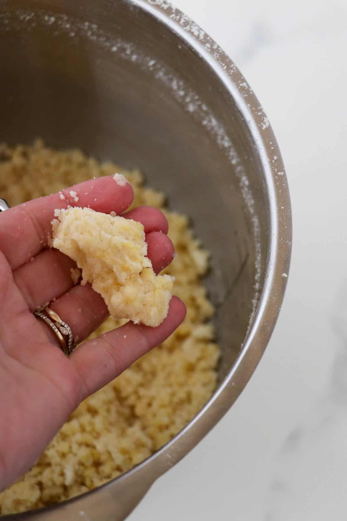 Person squeezing almond tart dough in their hand.