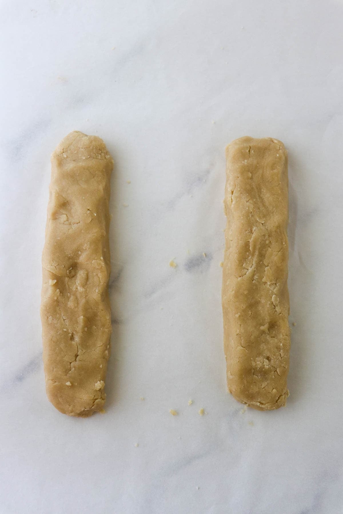Kolasnittar dough formed into two rough log shapes.