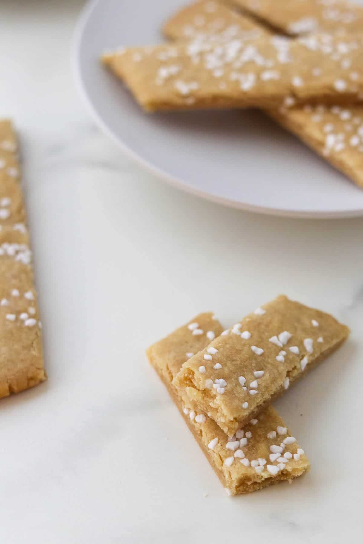 Kolasnittar cookie broken in half next to more cookies on a plate.