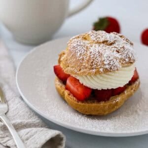 Cream puff filled with strawberries and whipped cream and sprinkled with powdered sugar.